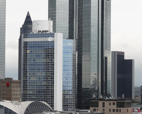 Frankfurter Hochhäuser mit dem Deutsche-Bank-Logo vor bewölktem Himmel.