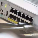 Nahaufnahme der Rückseite eines Cisco-Netzwerkgeräts mit Ethernet-Anschlüssen und angeschlossenen Kabeln.