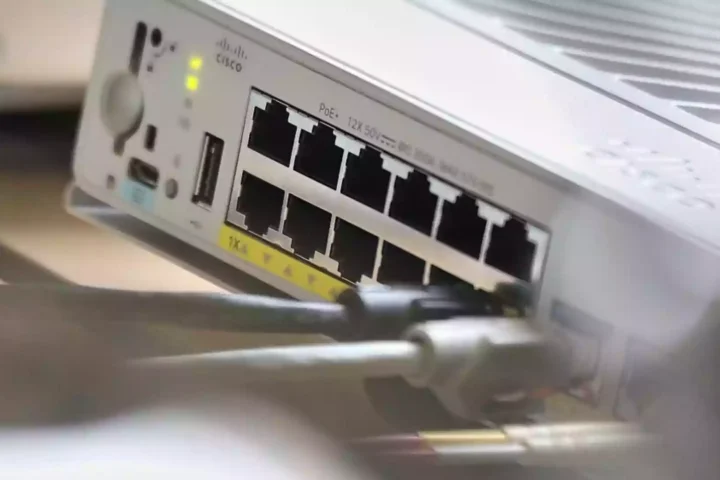 Nahaufnahme der Rückseite eines Cisco-Netzwerkgeräts mit Ethernet-Anschlüssen und angeschlossenen Kabeln.
