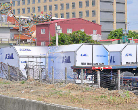 ASML-beschriftete Transportcontainer stehen auf einem Gelände vor Gebäuden.