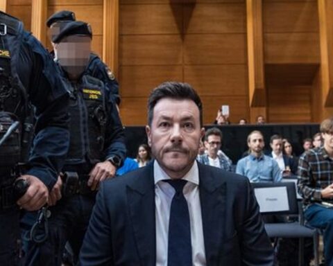 René Benko sitzt in einem Gerichtssaal, flankiert von Justizwachebeamten.