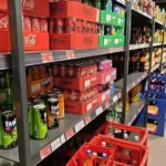 Supermarktregal mit Softdrinks und Markengetränken wie Cola, Fanta und weiteren Limonaden.