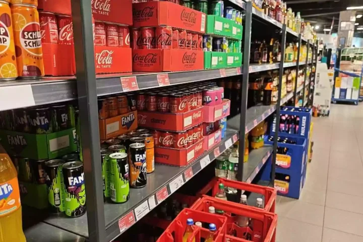 Supermarktregal mit Softdrinks und Markengetränken wie Cola, Fanta und weiteren Limonaden.