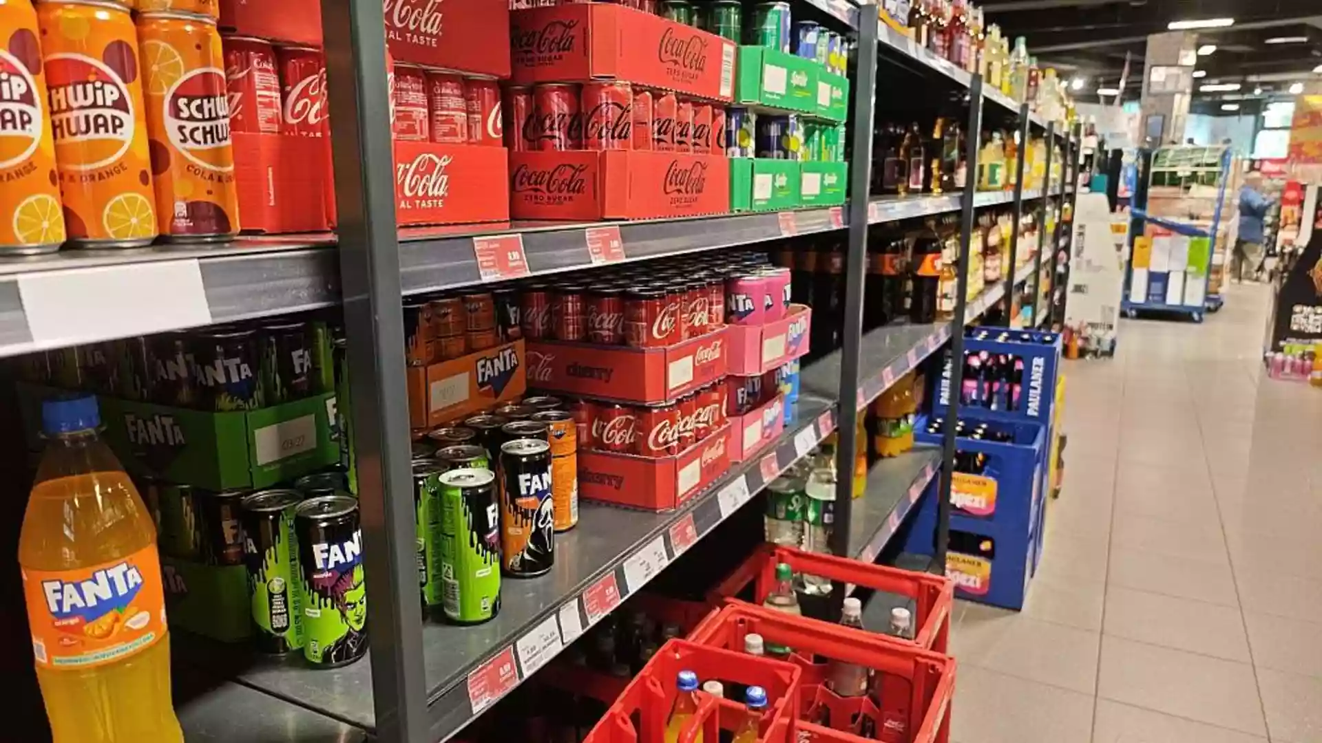 Supermarktregal mit Softdrinks und Markengetränken wie Cola, Fanta und weiteren Limonaden.