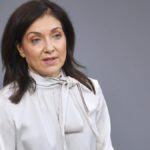 Katherina Reiche vor grauem Hintergrund bei einem öffentlichen Auftritt.