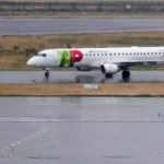 Ein TAP-Air-Portugal-Flugzeug rollt auf einer nassen Start- und Landebahn.