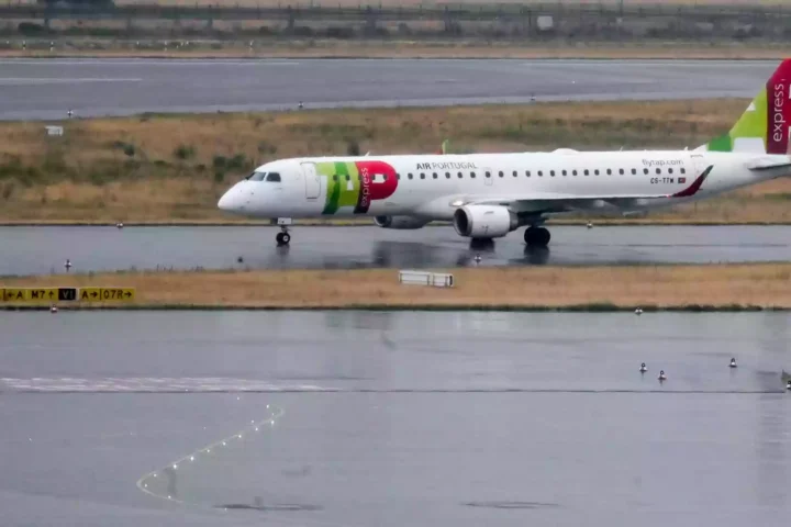 Ein TAP-Air-Portugal-Flugzeug rollt auf einer nassen Start- und Landebahn.