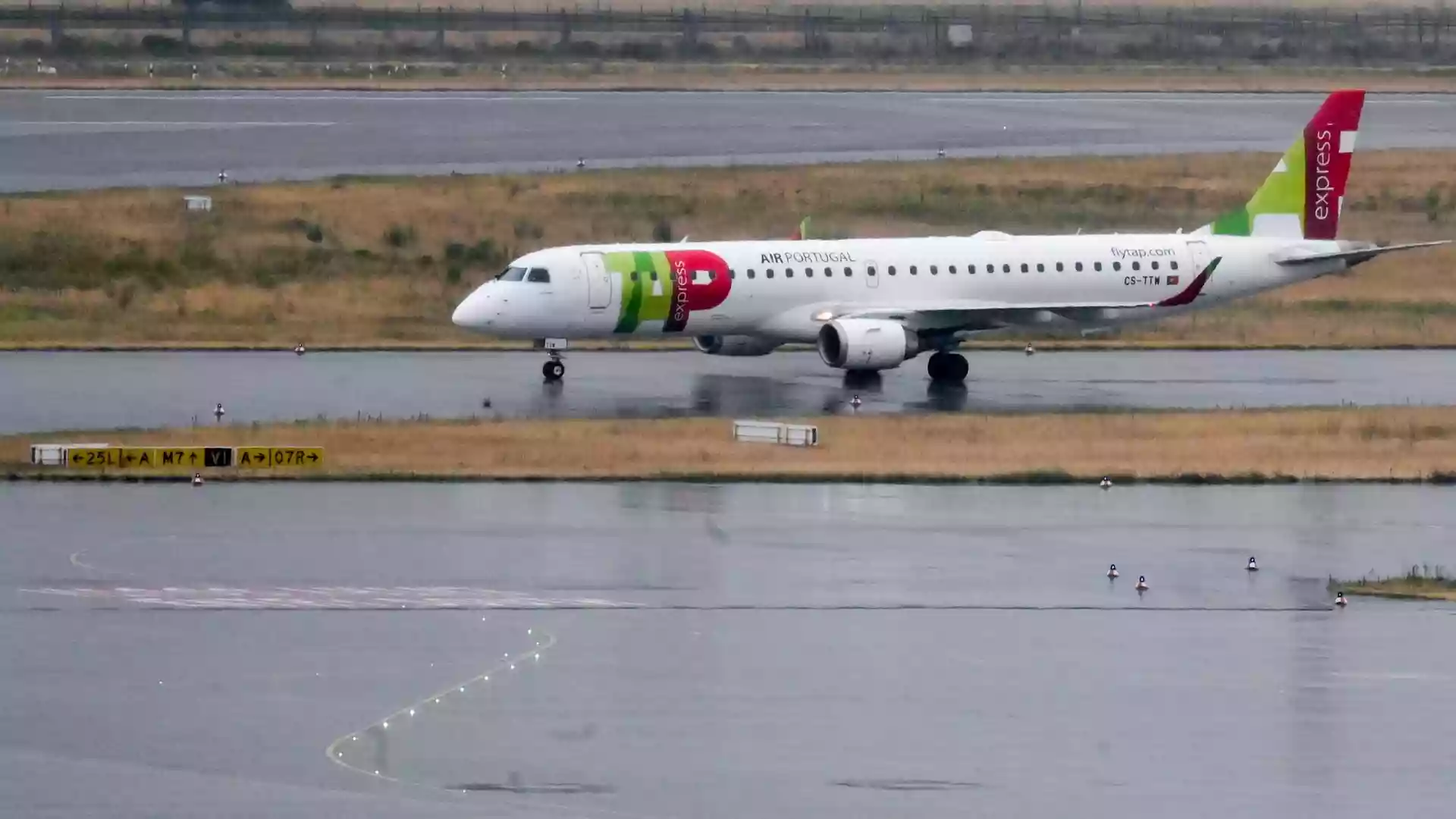 Ein TAP-Air-Portugal-Flugzeug rollt auf einer nassen Start- und Landebahn.