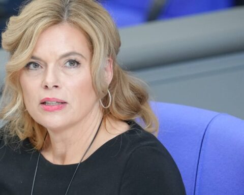 Julia Klöckner sitzt in einem hellen Saal auf einem blauen Stuhl und blickt zur Seite.