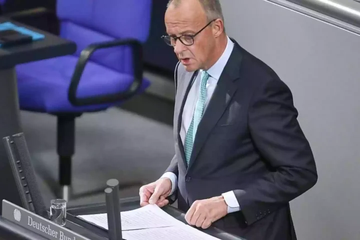 Friedrich Merz steht am Rednerpult im Deutschen Bundestag und blickt auf Unterlagen.