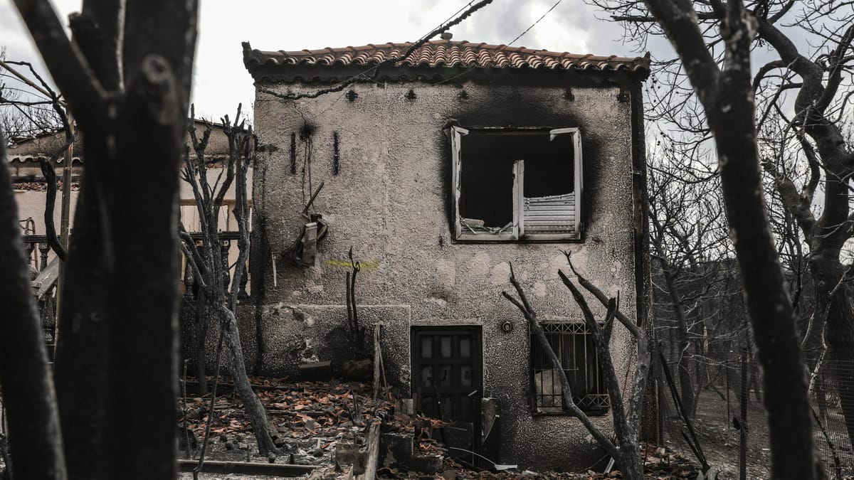 Versicherungsinsider warnen vor unversicherbaren Immobilien durch Klimarisiken 1 Ein durch Brand stark beschädigtes Wohnhaus mit verkohlter Fassade und zerstörten Fenstern zwischen verbrannten Bäumen.