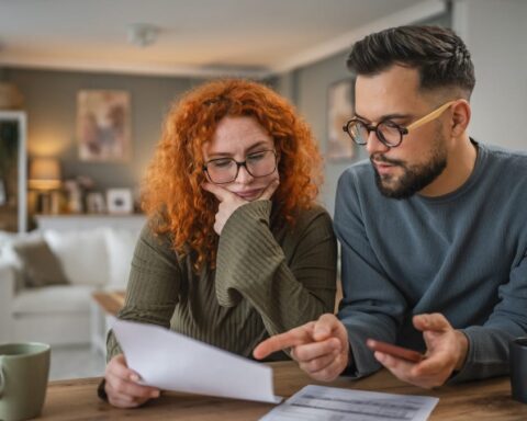 Ein Paar prüft gemeinsam Unterlagen am Tisch und bespricht Finanzen.