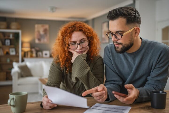 Ein Paar prüft gemeinsam Unterlagen am Tisch und bespricht Finanzen.