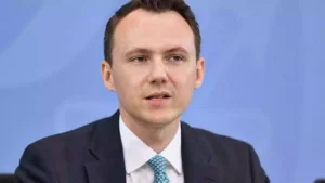 Pascal Reddig in dunklem Anzug vor blauem Hintergrund.
