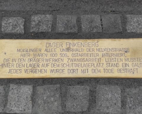 Gedenkplakette am Boden mit der Inschrift zum Lager Finkenberg und zum Zwangsarbeitseinsatz bei den Drägerwerken.