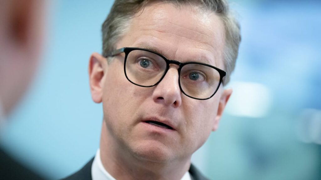 Carsten Linnemann in Nahaufnahme mit Brille vor blauem Hintergrund.