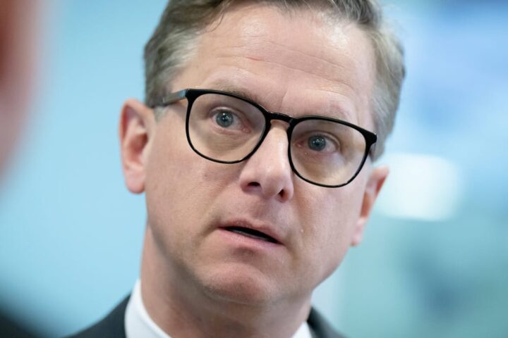 Carsten Linnemann in Nahaufnahme mit Brille vor blauem Hintergrund.