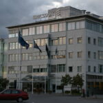 Ericsson-Firmengebäude mit Logo auf dem Dach unter bewölktem Himmel.
