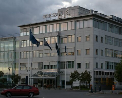 Ericsson-Firmengebäude mit Logo auf dem Dach unter bewölktem Himmel.