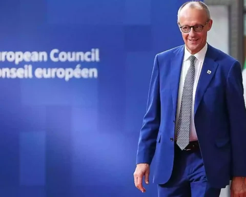 Friedrich Merz steht vor einer blauen European-Council-Wand neben einer EU-Flagge.
