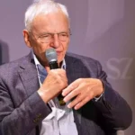 Götz Aly spricht mit einem Mikrofon bei einer Veranstaltung.