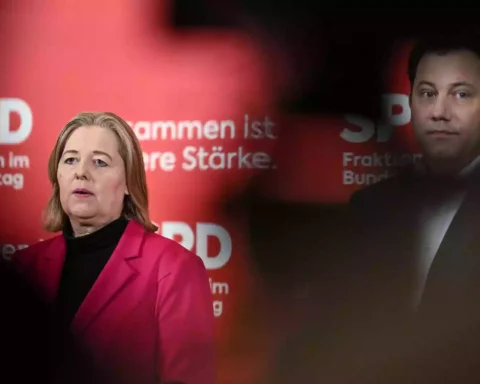 Zwei SPD-Politiker vor rotem Parteihintergrund mit SPD-Logo.