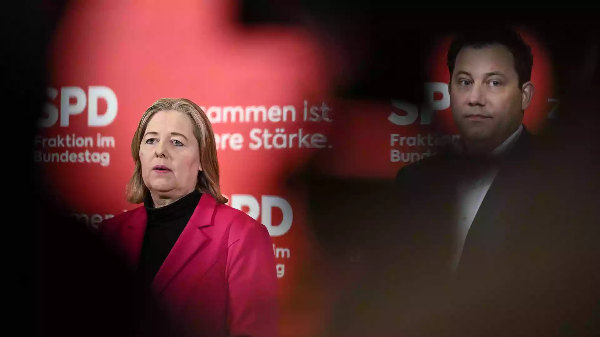 Zwei SPD-Politiker vor rotem Parteihintergrund mit SPD-Logo.
