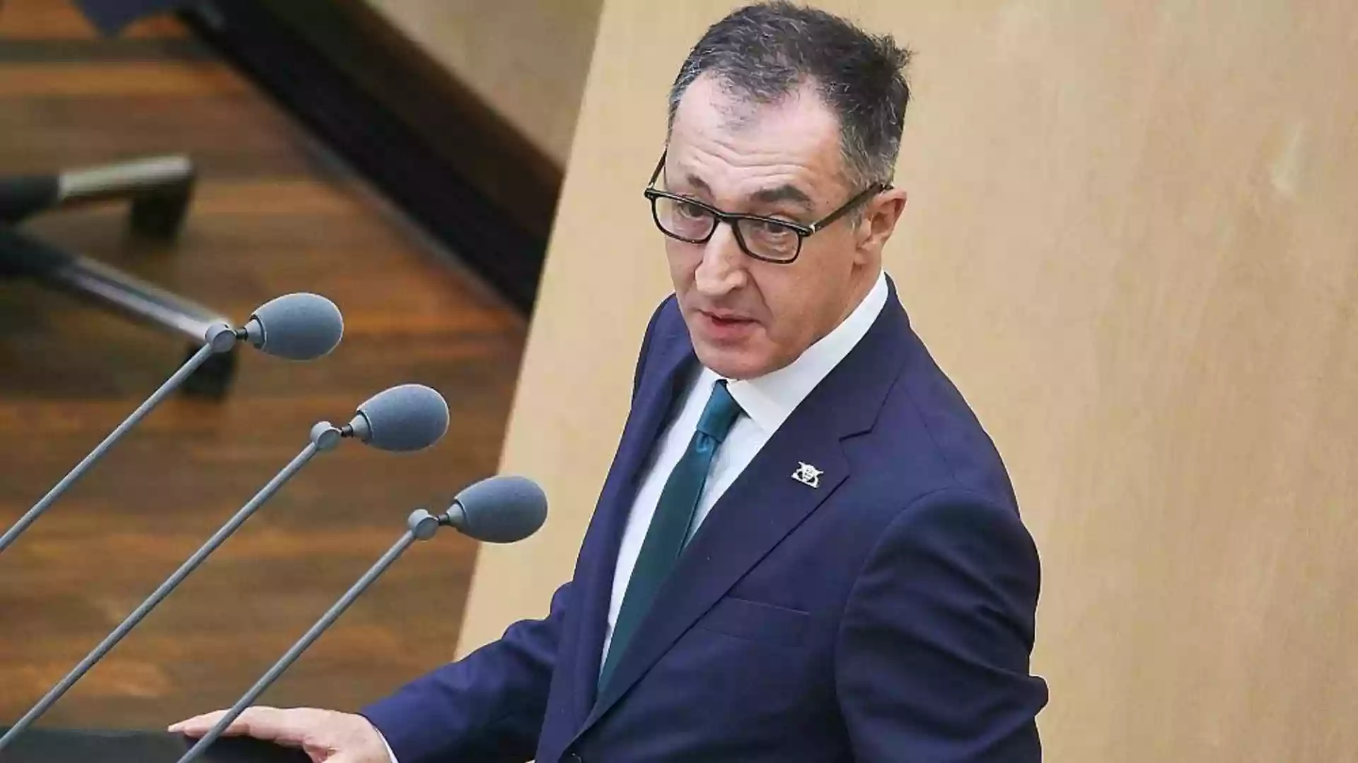 Infratest sieht Grüne in Baden-Württemberg mit 30 Prozent vorn 1 Ein Mann im Anzug spricht an einem Rednerpult im Plenarsaal.