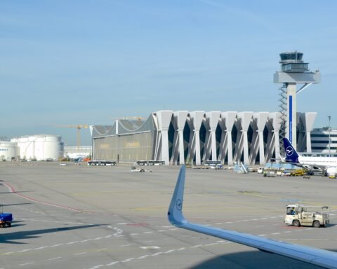 Lufthansa-Flugzeug auf dem Vorfeld am Flughafen Frankfurt mit Tower und Terminalgebäuden im Hintergrund.