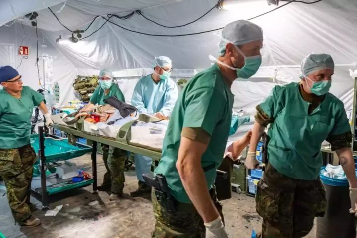 Sanitätspersonal arbeitet in einem provisorischen Feldlazarett mit Trage und medizinischer Ausrüstung.