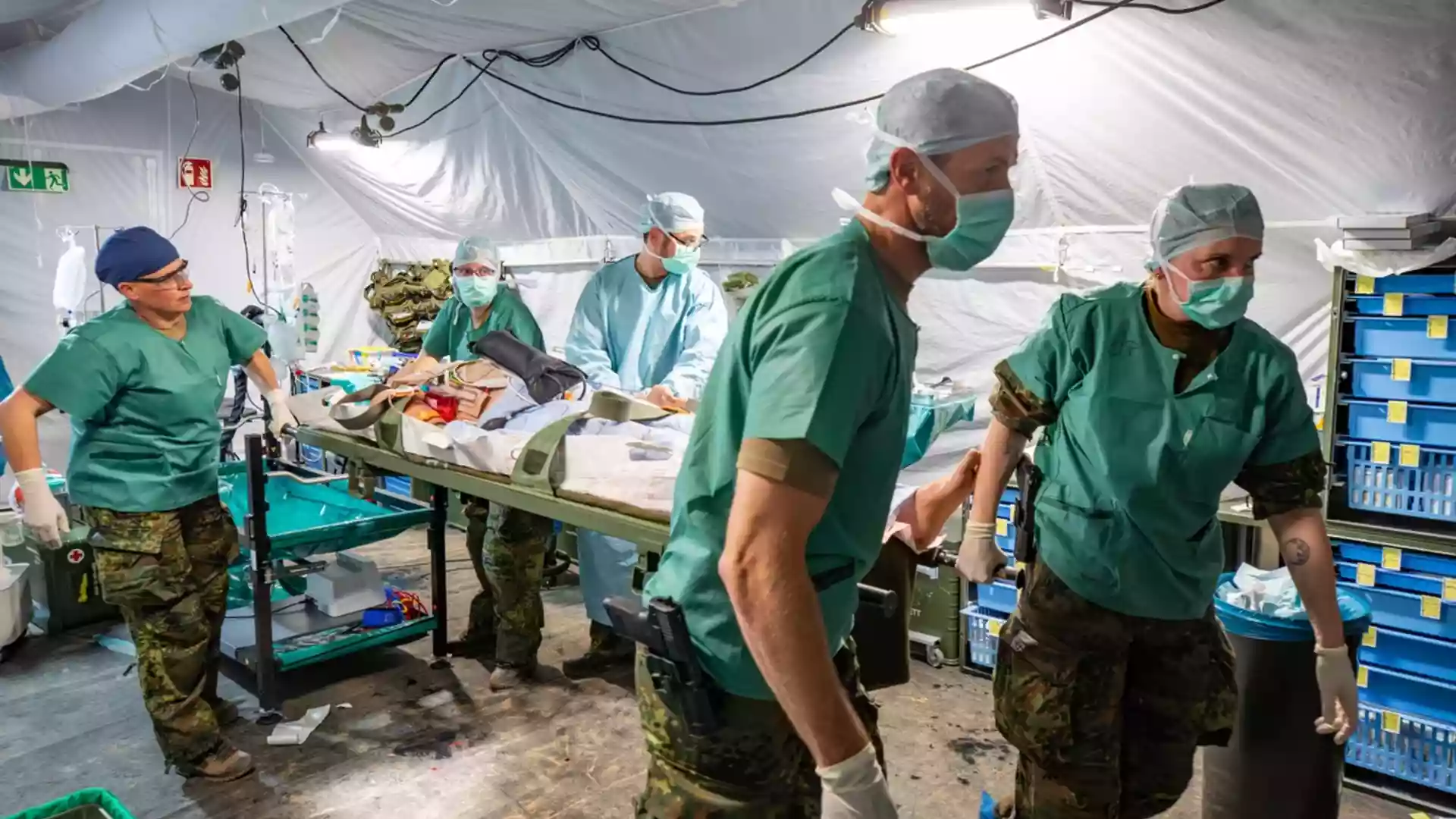 Sanitätspersonal arbeitet in einem provisorischen Feldlazarett mit Trage und medizinischer Ausrüstung.