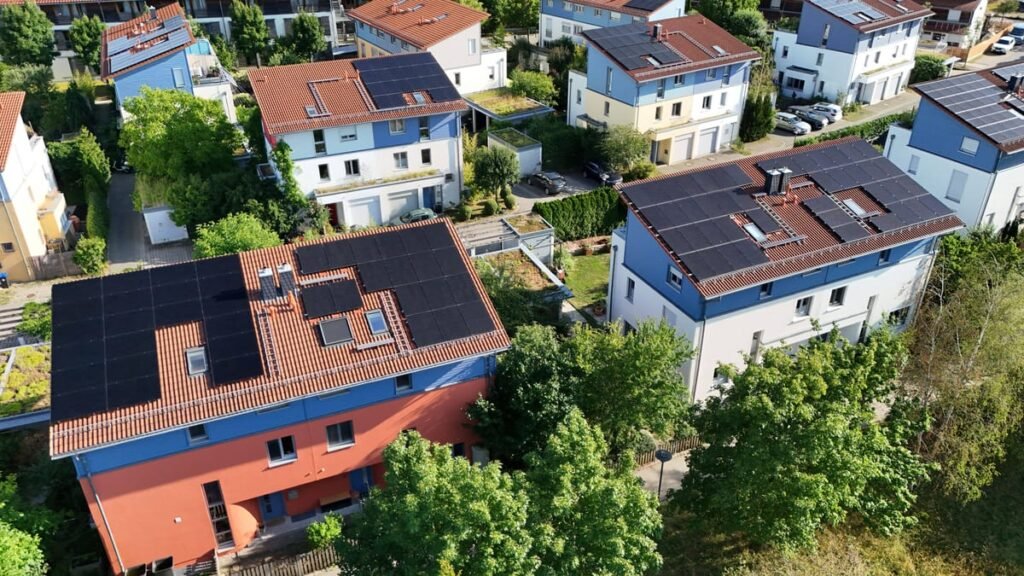 Luftaufnahme von Wohnhäusern mit Solaranlagen auf den Dächern in einem Wohngebiet.