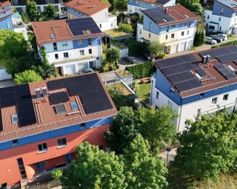 Luftaufnahme von Wohnhäusern mit Solaranlagen auf den Dächern in einem Wohngebiet.