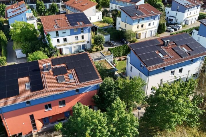 Luftaufnahme von Wohnhäusern mit Solaranlagen auf den Dächern in einem Wohngebiet.