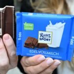 Hände halten zwei Ritter-Sport-Schokoladentafeln und eine Wacker-Verpackung mit der Aufschrift „Monnemer Quadrat Bio“.