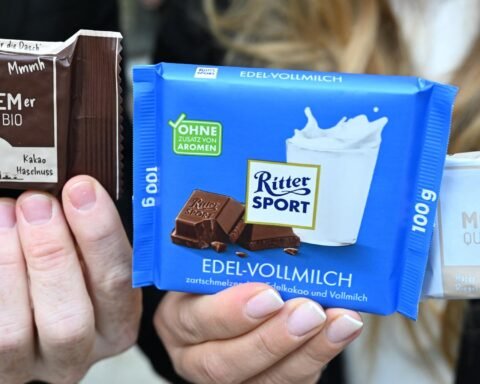 Hände halten zwei Ritter-Sport-Schokoladentafeln und eine Wacker-Verpackung mit der Aufschrift „Monnemer Quadrat Bio“.