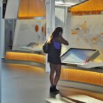 Eine Frau betrachtet eine interaktive Ausstellung mit Siemens-Branding in einem hellen Innenraum.