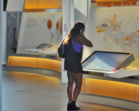 Eine Frau betrachtet eine interaktive Ausstellung mit Siemens-Branding in einem hellen Innenraum.