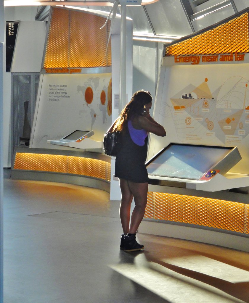 Jefferies stuft Siemens von Buy auf Hold herab und erhöht Kursziel 1 Eine Frau betrachtet eine interaktive Ausstellung mit Siemens-Branding in einem hellen Innenraum.