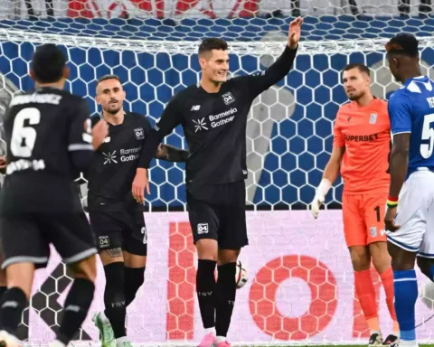 Bayer-Leverkusen-Spieler feiern vor dem Tor, während der gegnerische Torhüter und ein Verteidiger zuschauen.