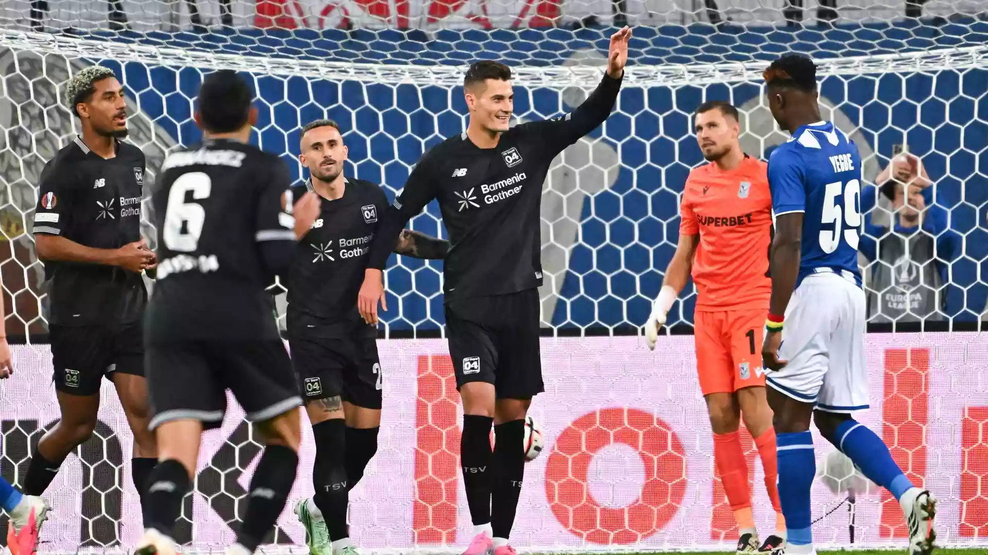 Bayer Leverkusen siegt in Posen 4:0 mit Schick-Doppelpack 1 Bayer-Leverkusen-Spieler feiern vor dem Tor, während der gegnerische Torhüter und ein Verteidiger zuschauen.