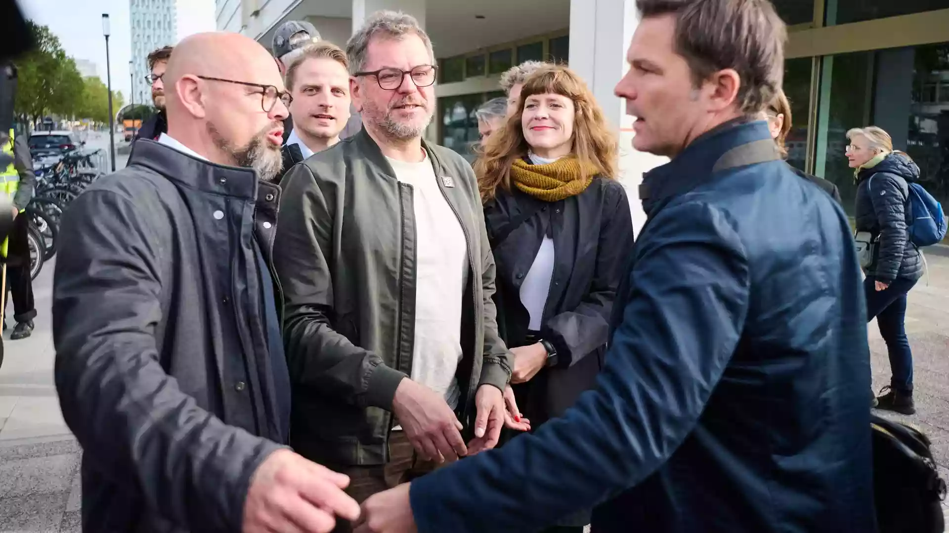 Mehrere Politikerinnen und Politiker stehen vor einem Gebäude im Gespräch.