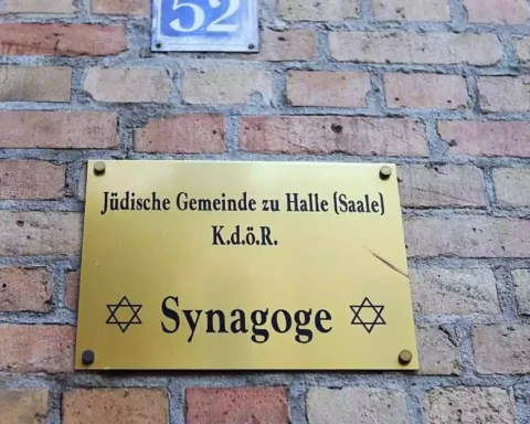 Schild an einer Backsteinwand mit der Aufschrift „Jüdische Gemeinde zu Halle (Saale)“ und „Synagoge“.