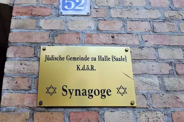 Schild an einer Backsteinwand mit der Aufschrift „Jüdische Gemeinde zu Halle (Saale)“ und „Synagoge“.