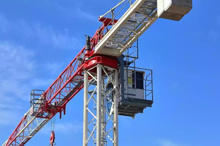 Baukran vor blauem Himmel auf einer Baustelle.