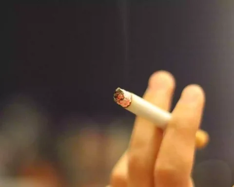 Eine Hand hält eine brennende Zigarette.