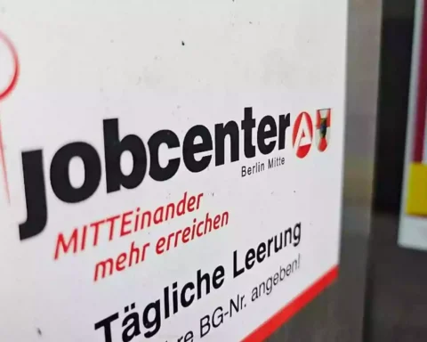 Schild mit der Aufschrift „jobcenter Berlin Mitte“ an einer Wand.