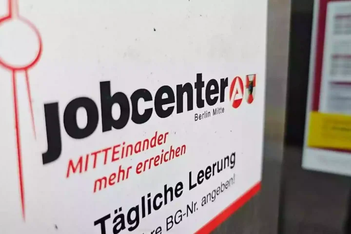 Schild mit der Aufschrift „jobcenter Berlin Mitte“ an einer Wand.