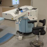 Ein Carl-Zeiss-Meditec-Lasergerät in einem Behandlungsraum mit Steuerkonsole, Monitor und Patientenstuhl.