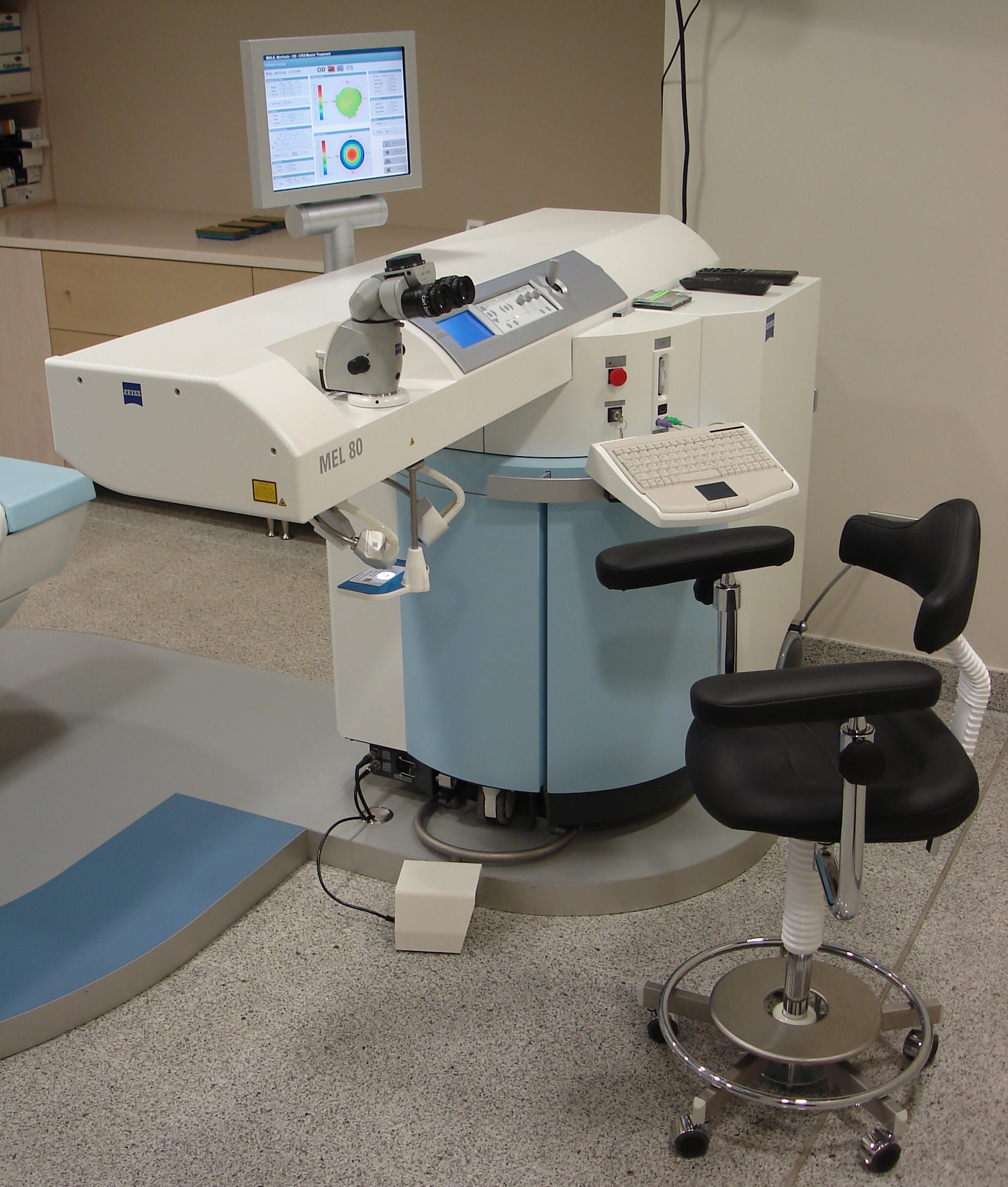 Ein Carl-Zeiss-Meditec-Lasergerät in einem Behandlungsraum mit Steuerkonsole, Monitor und Patientenstuhl.